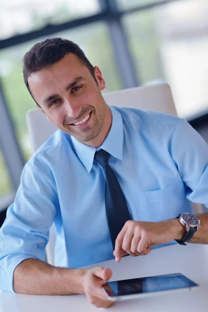 Man using a tablet looking at the camera and smiling.